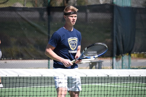 Grayson McCarty stands at the net during doubles play.
